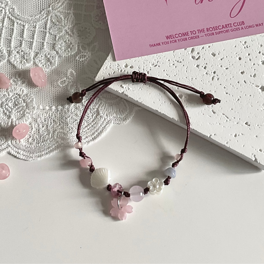 Beaded bracelet with pink and white stones on a textured surface with a card in the background.